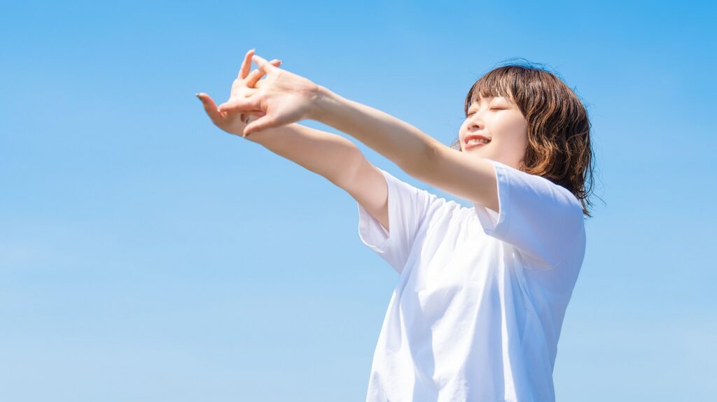 夏の青空と白いTシャツを着た笑顔の女